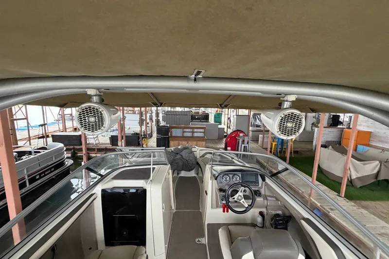 Slide: The Image of 2015 Yamaha Boats 242 Limited S interior with speakers and helm, docked in a marina. - 27