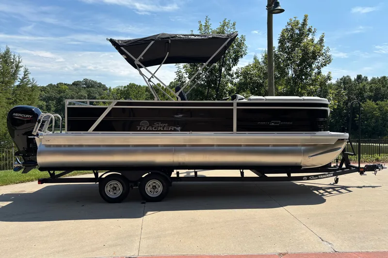 The Image of 2027 Sun Tracker Party Barge 22 RF DLX pontoon boat on trailer, parked outdoors. - 0