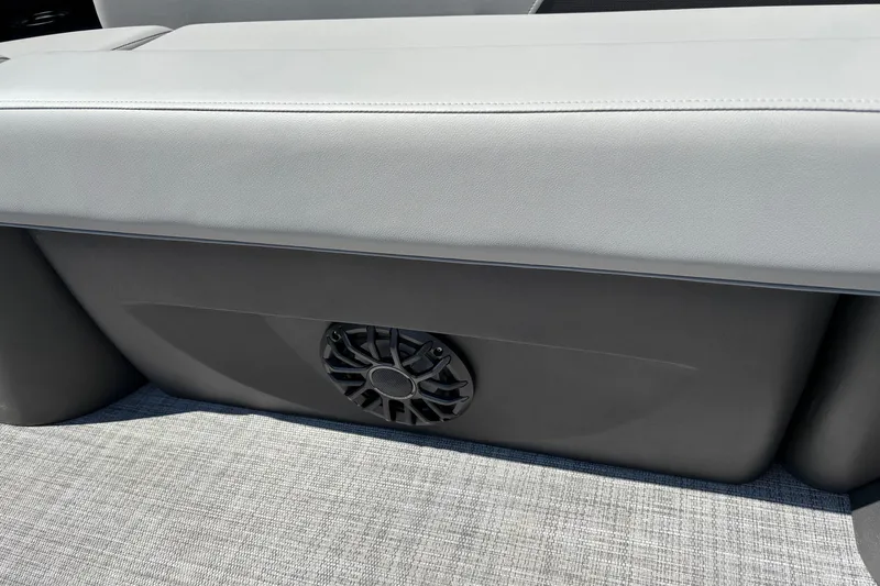 Slide: The Image of 2027 Sun Tracker Party Barge 22 RF DLX seat with integrated speaker on gray flooring. - 13