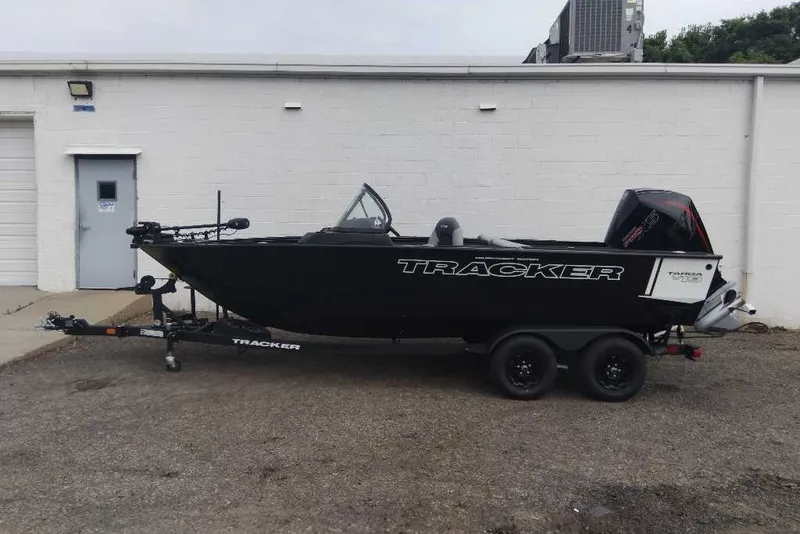 The Image of 2027 Tracker Targa V-19 Combo boat on trailer, parked beside a white building. - 0