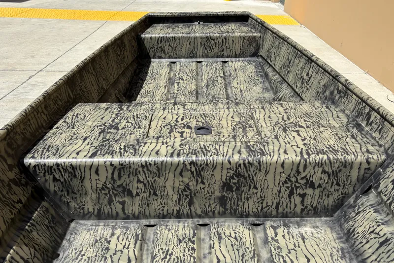Slide: The Image of 2027 Tracker Grizzly 15 Jon boat with camouflage interior design, parked outdoors. - 16