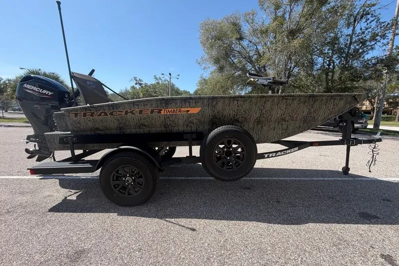 The Image of 2027 Tracker Grizzly 1553 Timber boat on trailer, parked outdoors, featuring Mercury engine. - 0