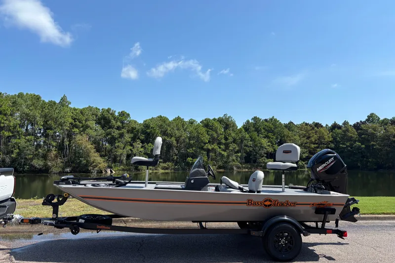 The Image of 2027 Tracker Bass Tracker Classic Limited boat by a lake under clear blue sky. - 0