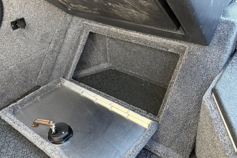 Slide: The Image of 2027 Tracker Targa V-19 Combo boat storage compartment with carpeted interior and latch. - 29