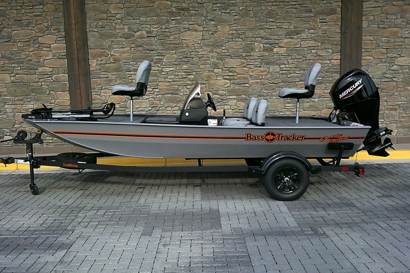 The Image of 2027 Tracker Bass Tracker Classic Limited fishing boat on trailer, parked against stone wall. - 0