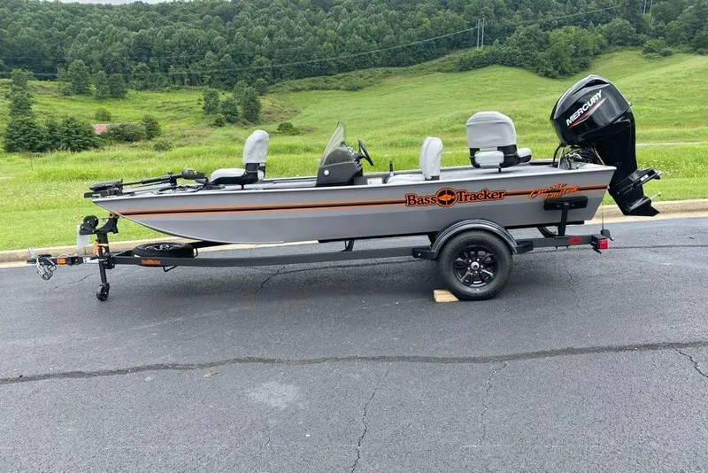 The Image of 2027 Tracker Bass Tracker Classic Limited boat on trailer, parked on asphalt with green hills background. - 0