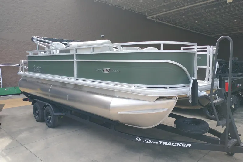 The Image of 2027 Sun Tracker Fishin' Barge 20 DLX pontoon boat on trailer in warehouse. - 0