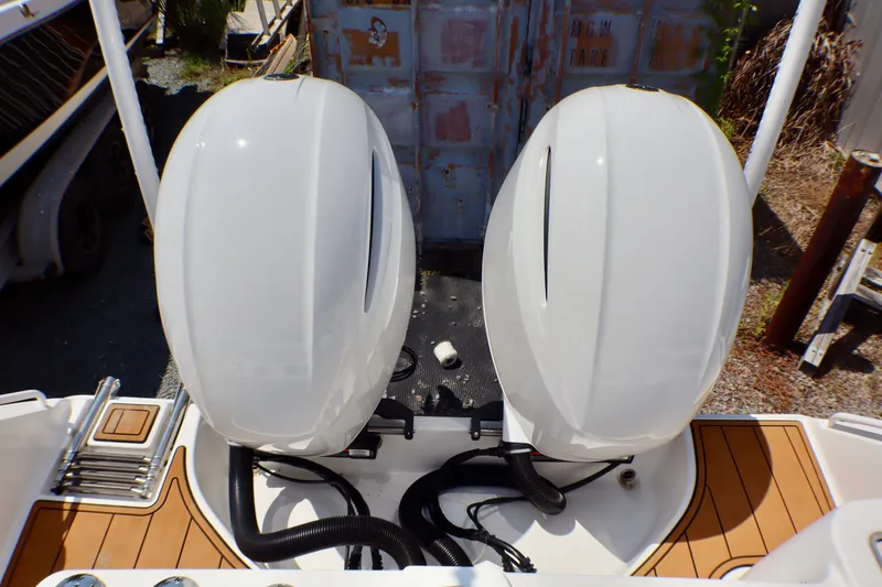 Slide: The Image of Twin outboard engines on a 2023 Edgewater 262CX Crossover boat, docked outdoors. - 48