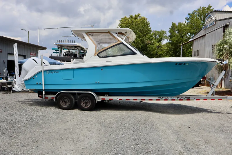 Slide: The Image of A 2023 Edgewater 262CX Crossover on a trailer, featuring a blue hull and white superstructure. - 26