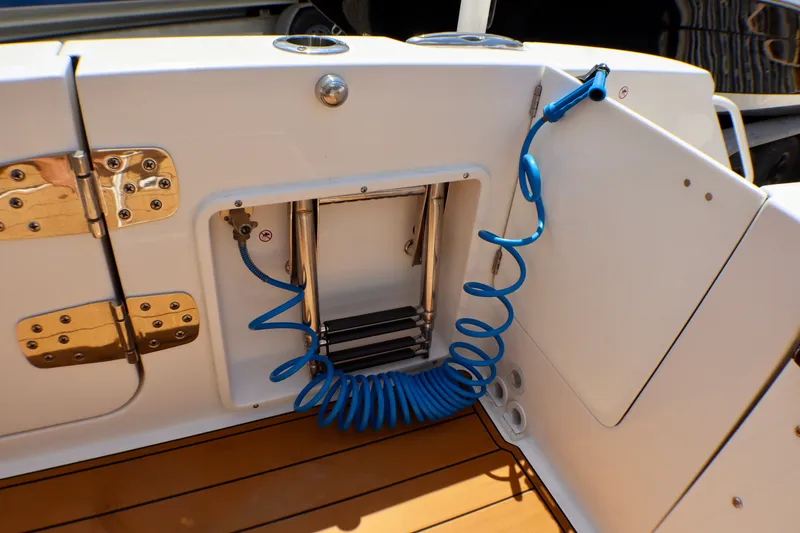 Slide: The Image of 2023 Edgewater 262CX Crossover boat deck with blue coiled hose and stainless steel fittings. - 49