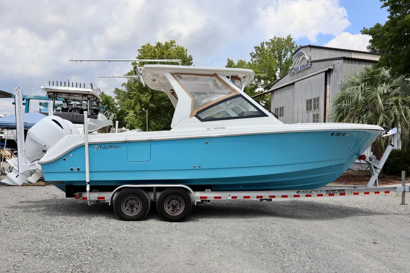 Slide: The Image of 2023 Edgewater 262CX Crossover boat on trailer, blue hull, outdoor setting. - 15