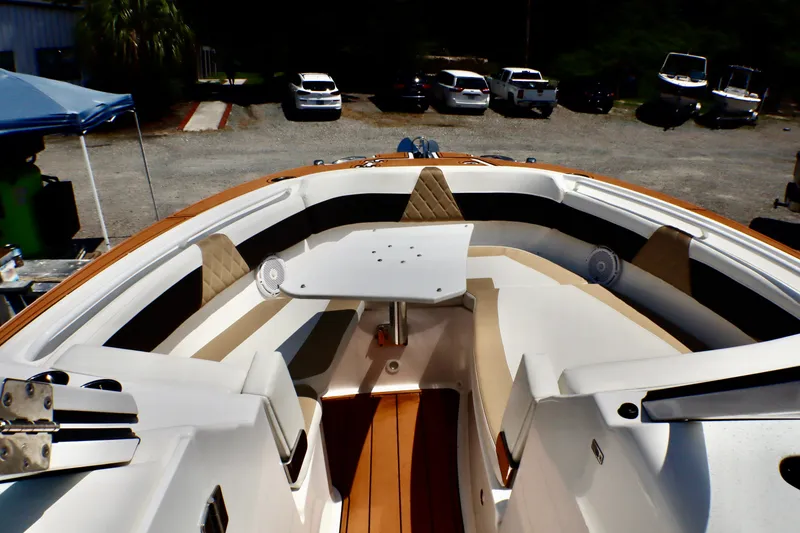 Slide: The Image of 2023 Edgewater 262CX Crossover boat interior with seating and table, parked outdoors. - 50