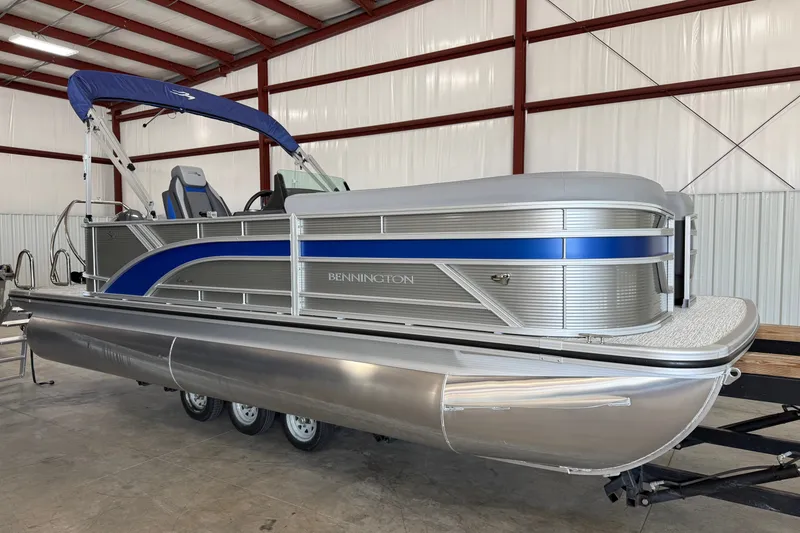 The Image of 2027 Bennington 22 SSR pontoon boat with blue accents in a warehouse setting. - 0
