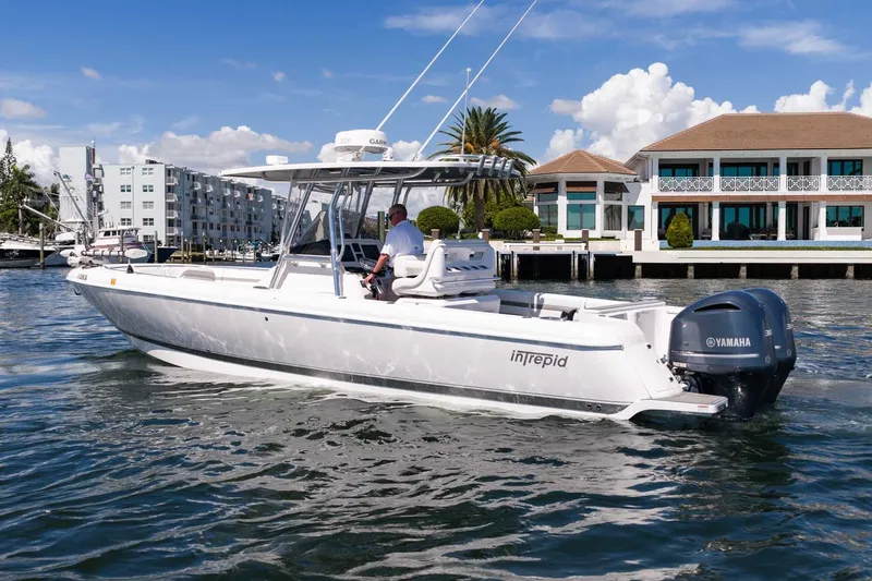 Slide: The Image of Intrepid 327 Nomad 2021 boat cruising near waterfront homes, featuring Yamaha engines. - 7