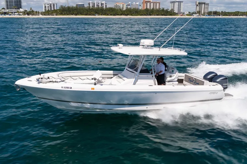 Slide: The Image of 2021 Intrepid 327 Nomad boat cruising on ocean near city skyline. - 2