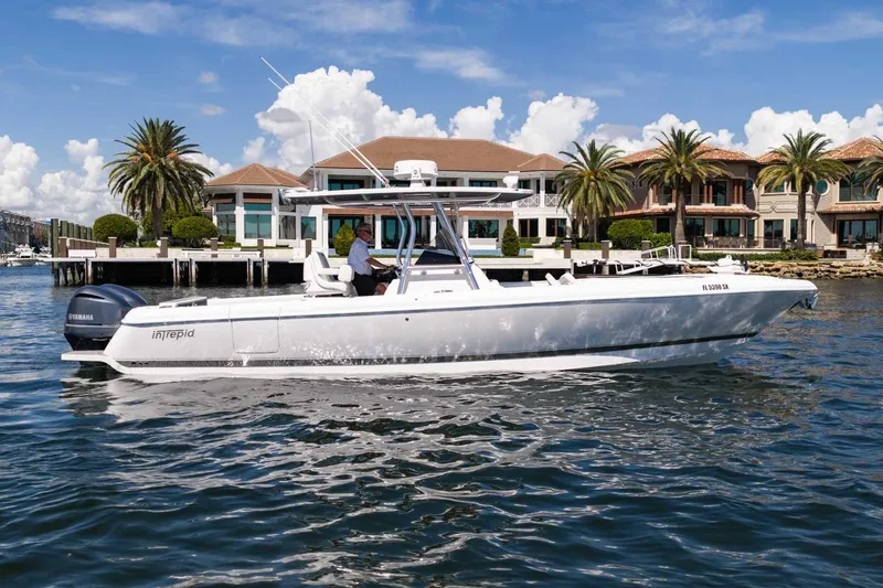 Slide: The Image of 2021 Intrepid 327 Nomad boat cruising near waterfront homes with palm trees. - 12
