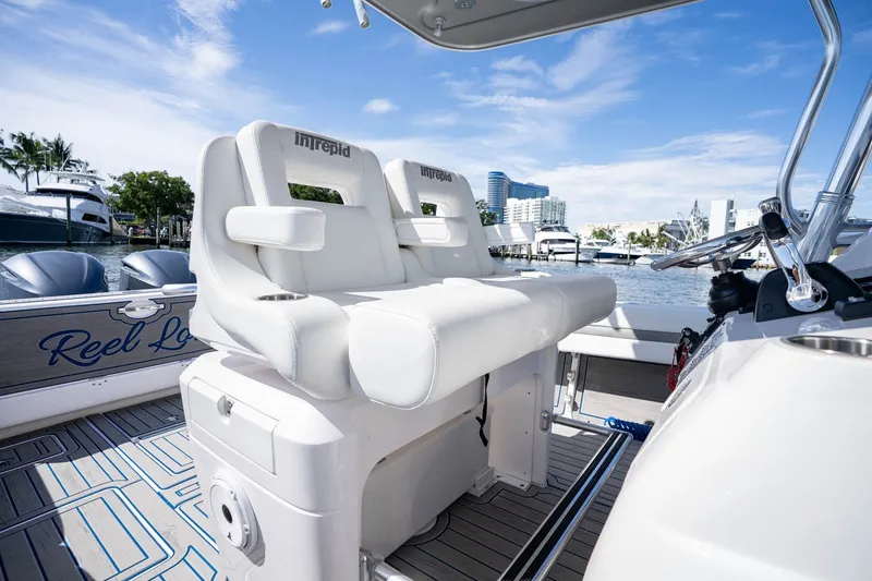 Slide: The Image of 2021 Intrepid 327 Nomad boat interior with white seating, docked in a marina. - 24