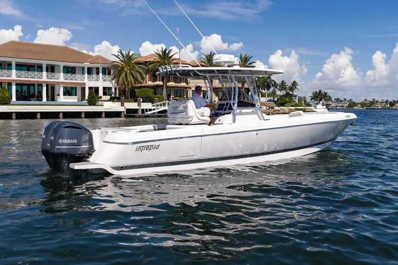 Slide: The Image of 2021 Intrepid 327 Nomad boat cruising near waterfront homes under a clear blue sky. - 11