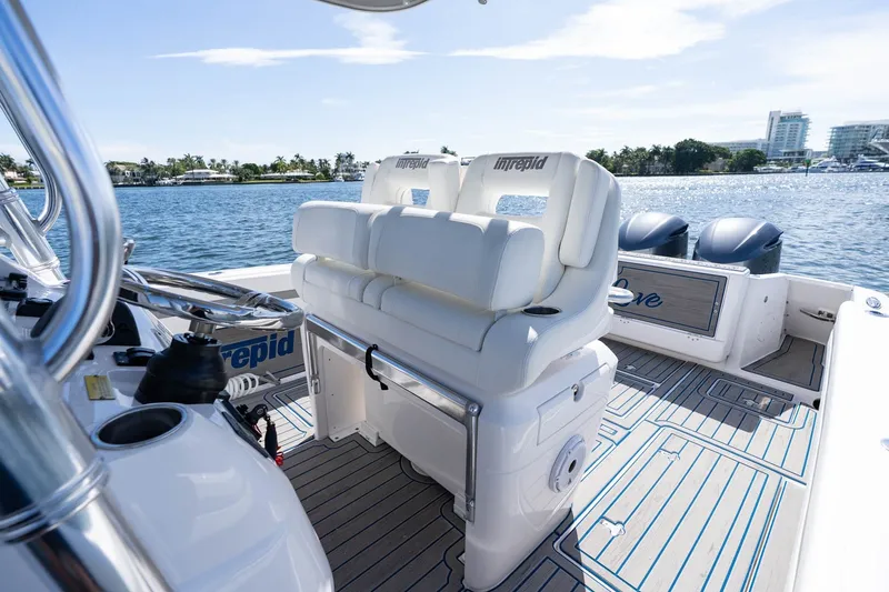 Slide: The Image of 2021 Intrepid 327 Nomad boat interior with white seating and dual engines on a sunny day. - 23