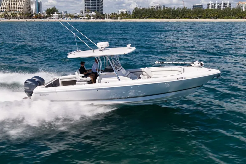 The Image of 2021 Intrepid 327 Nomad boat cruising on ocean near city skyline. - 0