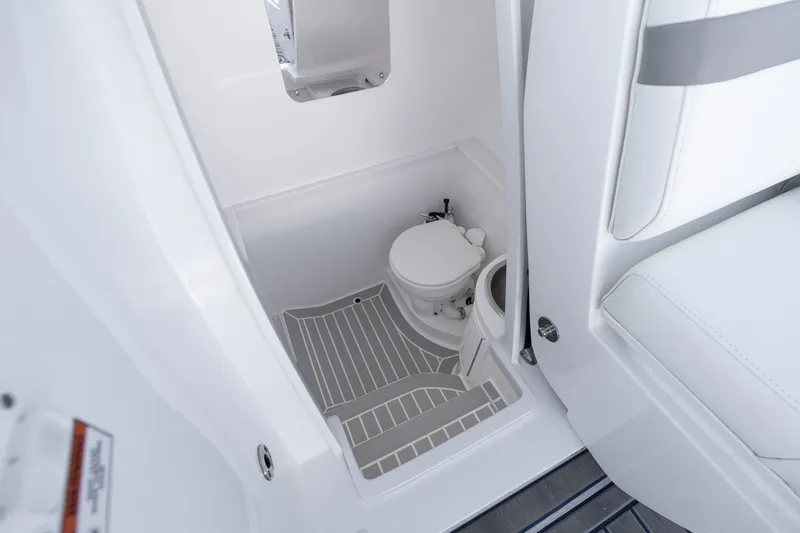 Slide: The Image of 2021 Intrepid 327 Nomad boat interior with compact marine toilet and seating. - 39