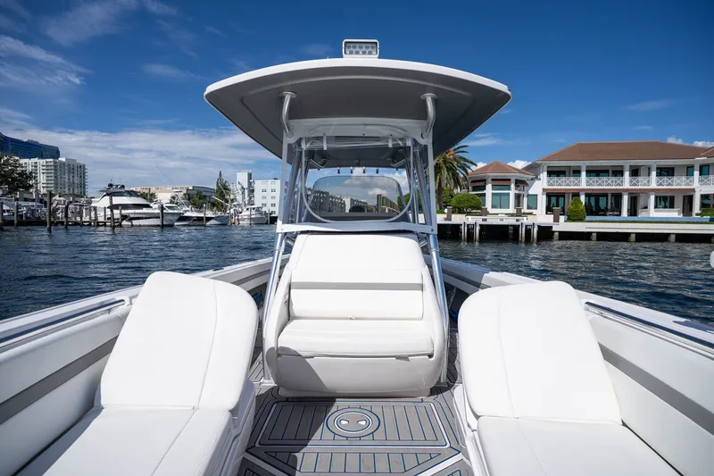 Slide: The Image of 2021 Intrepid 327 Nomad boat with white seating, docked near waterfront homes. - 31