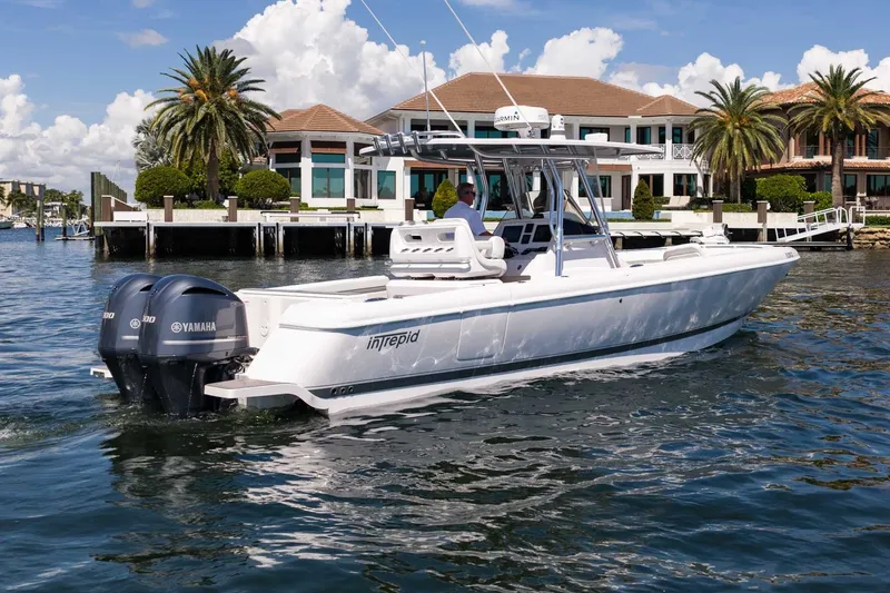 Slide: The Image of 2021 Intrepid 327 Nomad boat cruising near waterfront homes, featuring twin Yamaha engines. - 10
