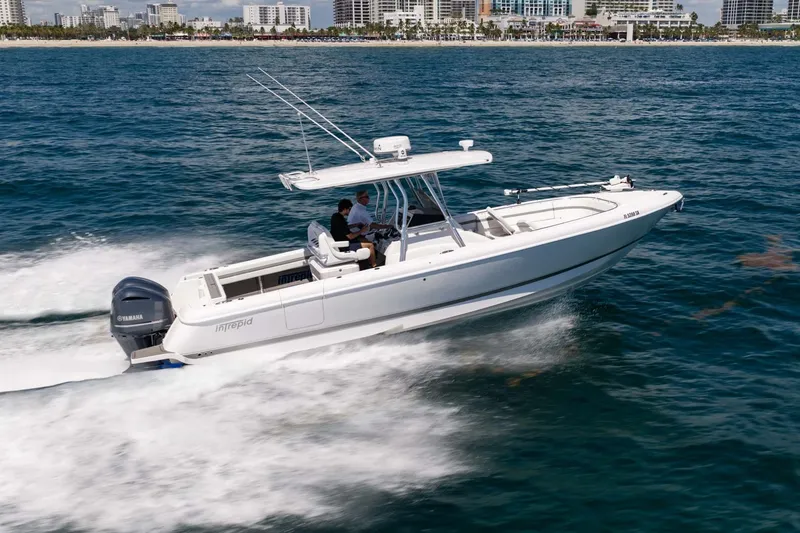Slide: The Image of 2021 Intrepid 327 Nomad boat cruising on ocean near city skyline. - 6