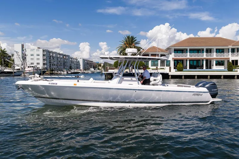 Slide: The Image of 2021 Intrepid 327 Nomad boat cruising near waterfront buildings under a clear sky. - 5