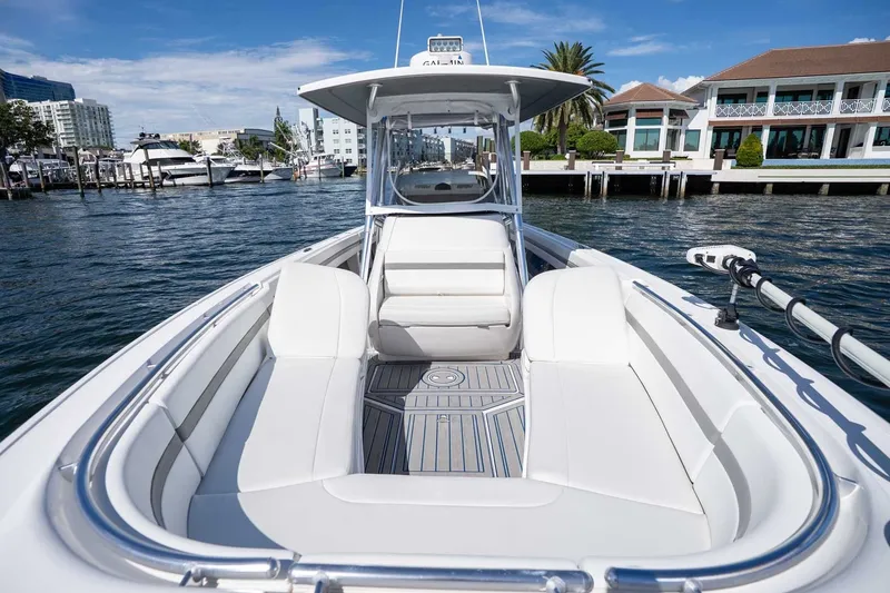 Slide: The Image of 2021 Intrepid 327 Nomad boat with sleek white seating, docked near waterfront homes. - 30