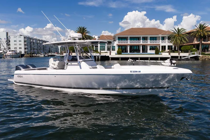 Slide: The Image of 2021 Intrepid 327 Nomad boat cruising near waterfront homes under a clear blue sky. - 13