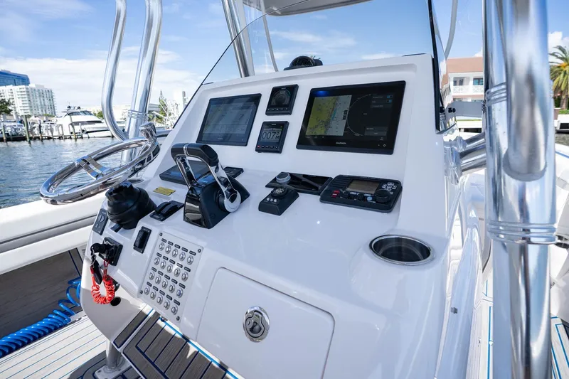 Slide: The Image of Control panel of a 2021 Intrepid 327 Nomad boat with navigation screens and steering wheel. - 22