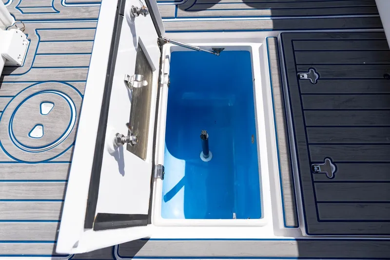 Slide: The Image of Open storage compartment on 2021 Intrepid 327 Nomad boat deck, featuring blue interior. - 37