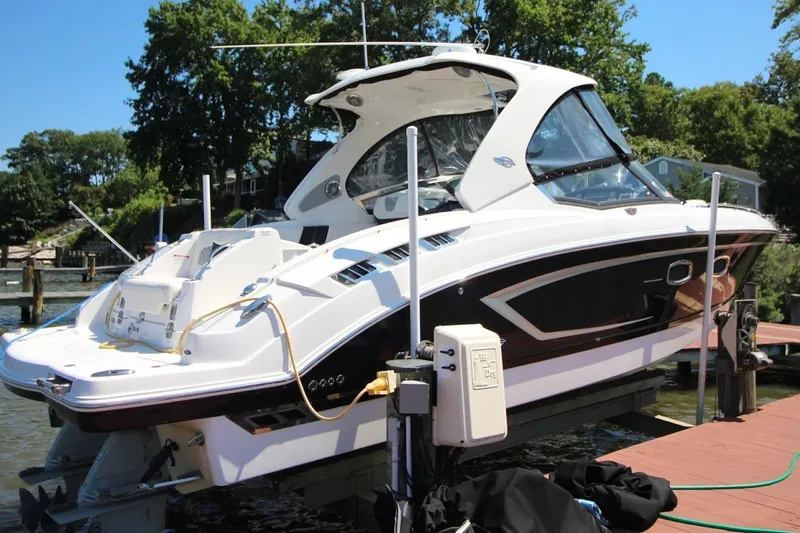 The Image of 2012 Chaparral 327 SSX boat docked on a sunny day with lush greenery. - 0