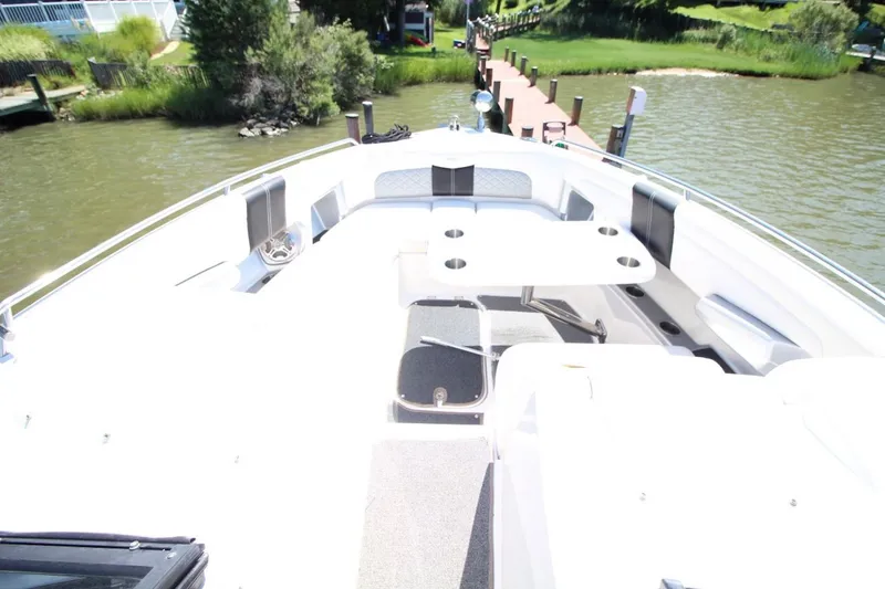 Slide: The Image of 2012 Chaparral 327 SSX boat interior with seating and table, docked by a scenic waterfront. - 19