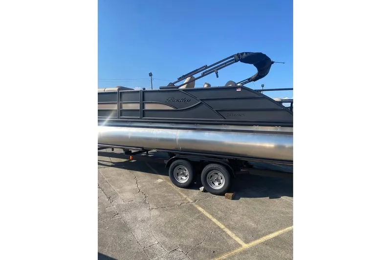 Slide: The Image of 2026 Bentley Pontoons Legacy 243 Swingback on trailer, parked outdoors under clear sky. - 16