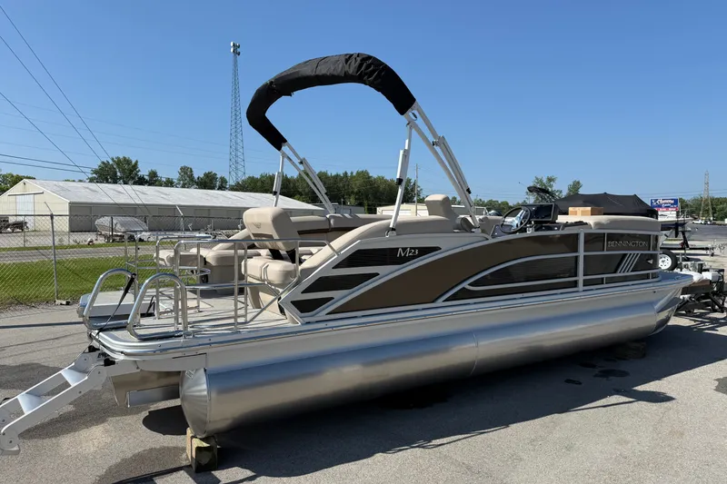 Slide: The Image of 2027 Bennington 23 MSL pontoon boat with canopy, parked outdoors on a sunny day. - 2