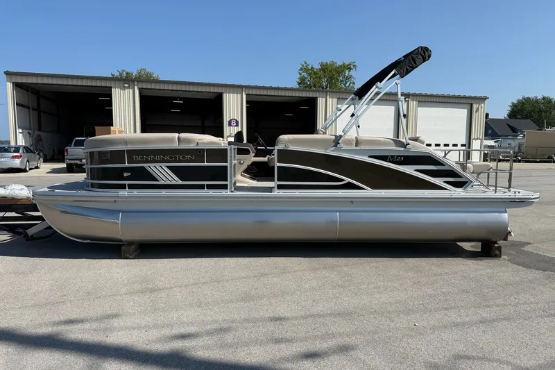 Slide: The Image of 2027 Bennington 23 MSL pontoon boat parked outside a warehouse. - 1