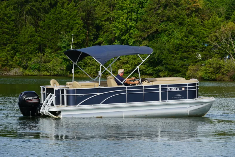 Slide: The Image of 2018 Bennington 22 SSX pontoon boat cruising on a serene lake. - 9