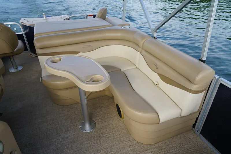 Slide: The Image of 2018 Bennington 22 SSX pontoon boat interior with beige seating and table on water. - 15