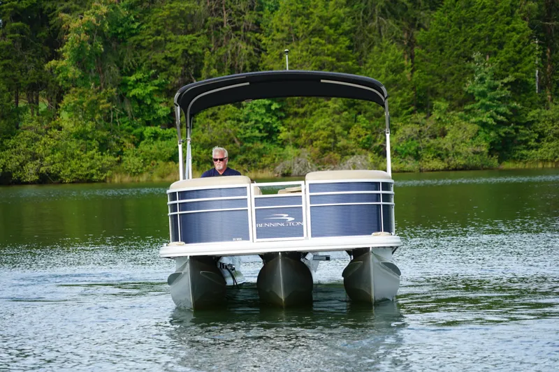 Slide: The Image of 2018 Bennington 22 SSX pontoon boat cruising on a serene lake. - 3