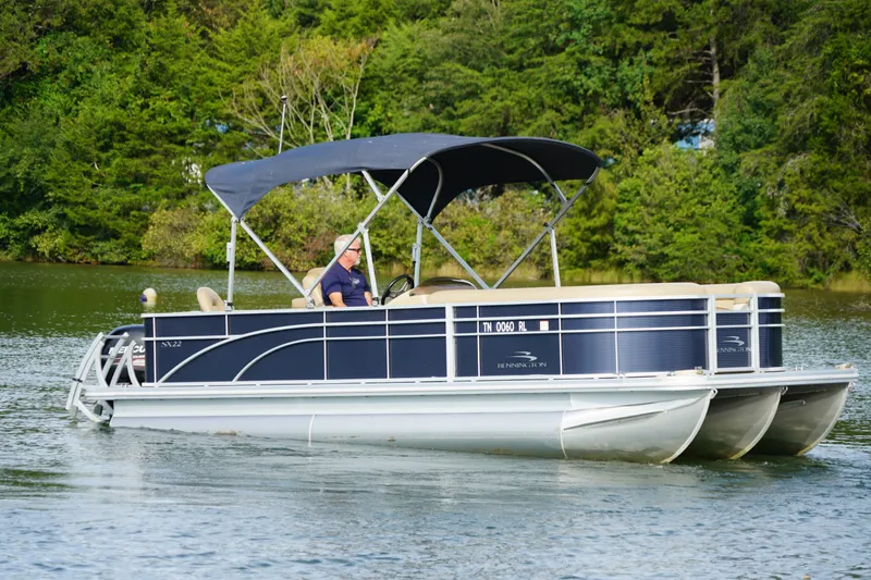 Slide: The Image of 2018 Bennington 22 SSX pontoon boat cruising on a lake with lush green trees. - 8