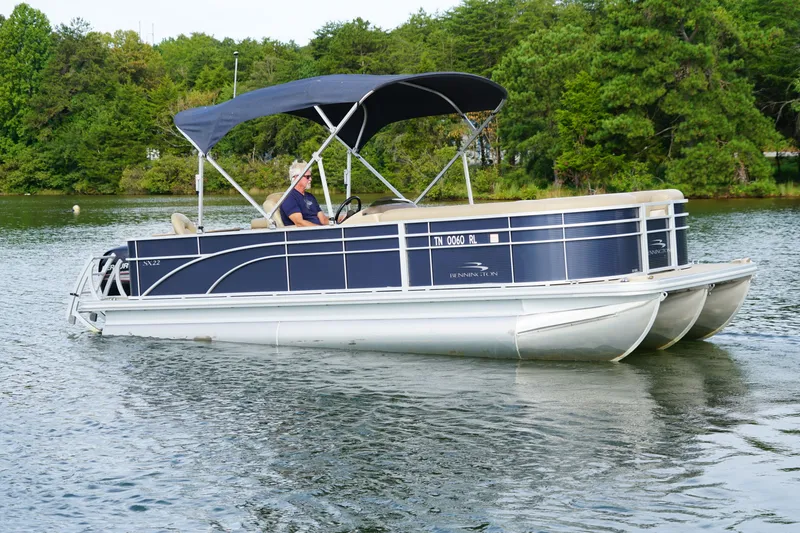 Slide: The Image of 2018 Bennington 22 SSX pontoon boat cruising on a scenic lake. - 1