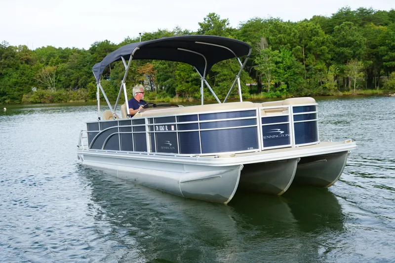 Slide: The Image of 2018 Bennington 22 SSX pontoon boat cruising on a lake with lush green trees. - 2