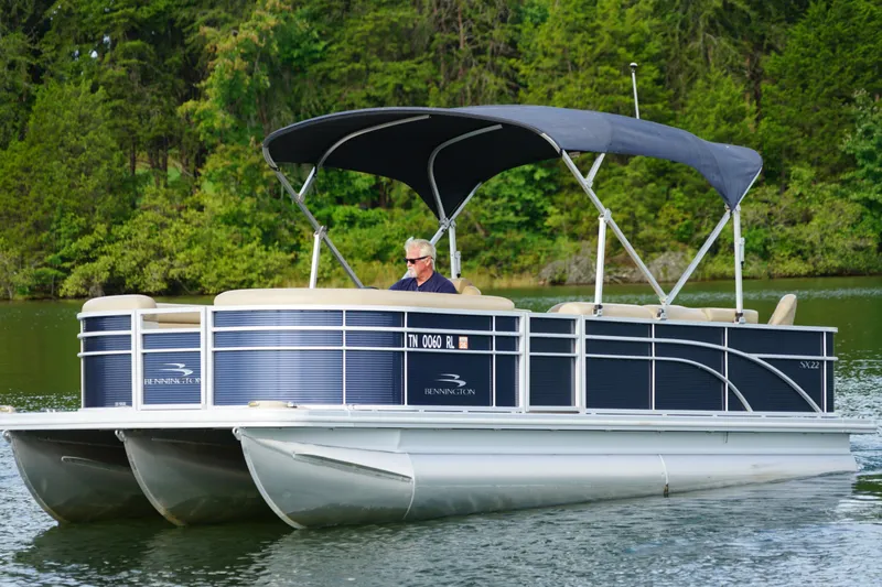The Image of 2018 Bennington 22 SSX pontoon boat cruising on a serene lake. - 0