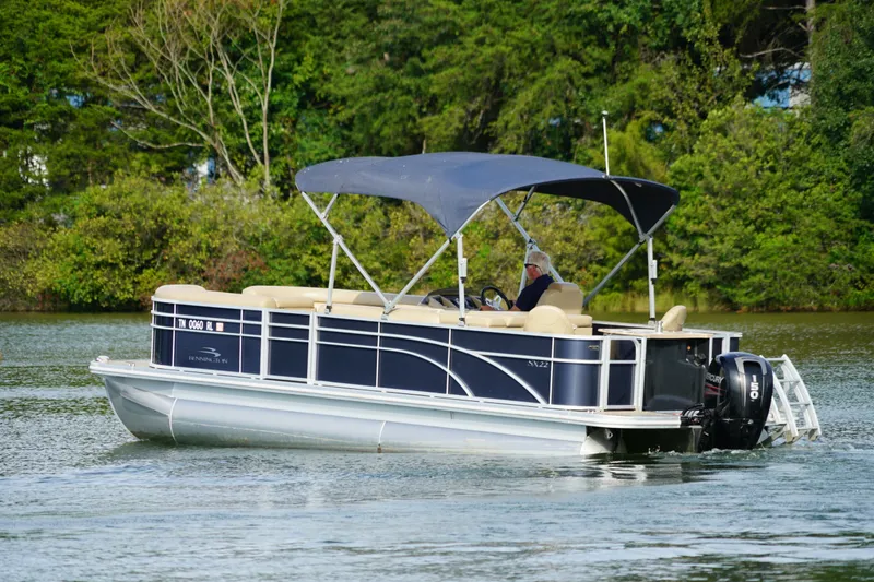 Slide: The Image of 2018 Bennington 22 SSX pontoon boat cruising on a serene lake. - 6