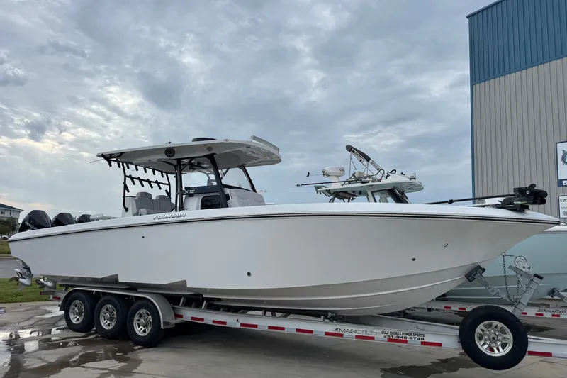 The Image of 2024 Fountain 34 Tournament Edition boat on trailer, parked outdoors under cloudy sky. - 1