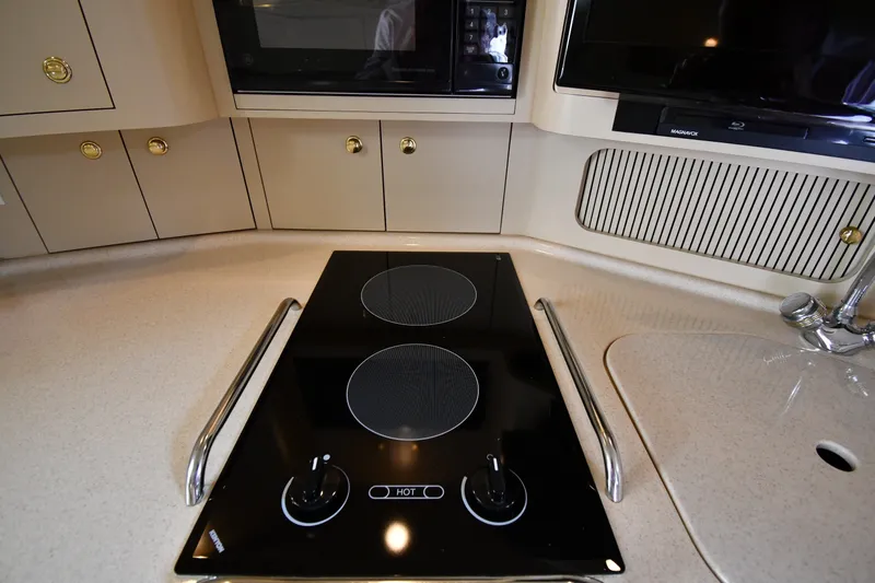 Slide: The Image of Modern kitchen area in a 2000 Sea Ray 330 Express Cruiser with stovetop and cabinetry. - 28