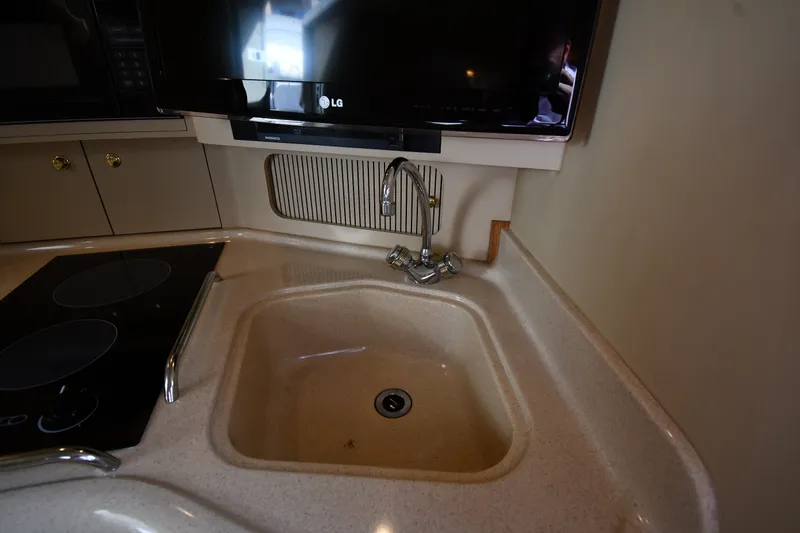 Slide: The Image of 2000 Sea Ray 330 Express Cruiser kitchen with sink, faucet, and TV. - 27