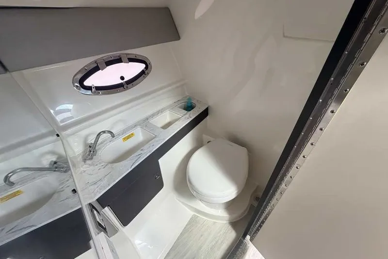 Slide: The Image of 2018 Formula 290 Sun Sport boat bathroom with sink, toilet, and porthole window. - 43